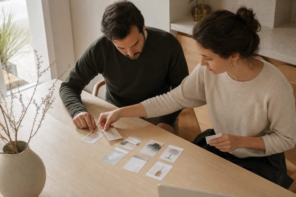 Hands laying printed cards into ordered columns on a table, like pipeline stages.